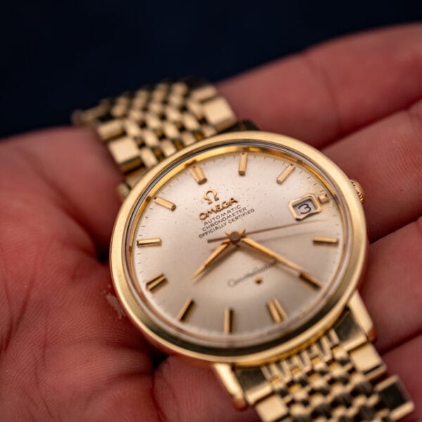Omega Constellation 168.004 in hand, close angle showing silver dial speckling and gold dauphine hands