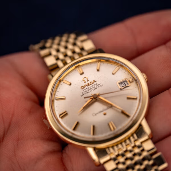 Omega Constellation 168.004 in hand, close angle showing silver dial speckling and gold dauphine hands
