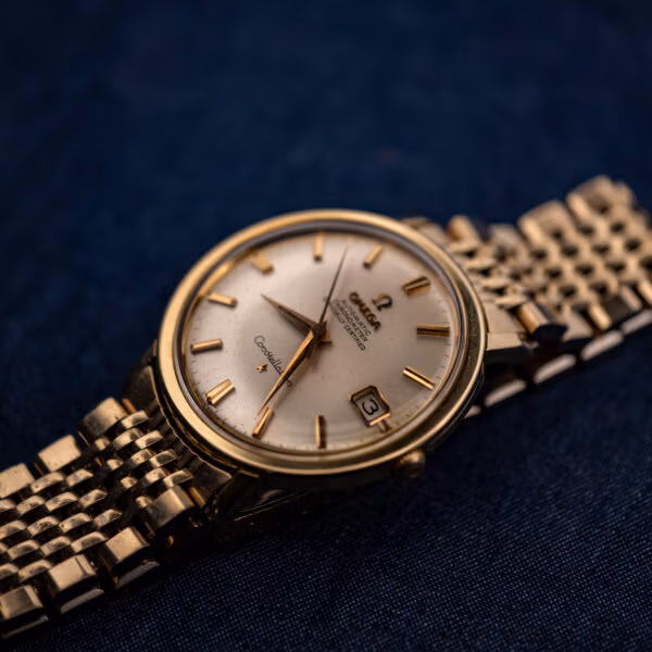 Omega Constellation 168.004 angled beauty shot, gold-capped case and silver sunburst chronometer dial on blue