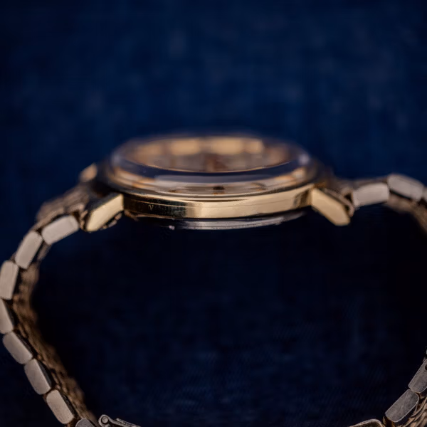 Omega Constellation 168.004 side profile showing the slim gold-capped case band and faceted downturned lugs