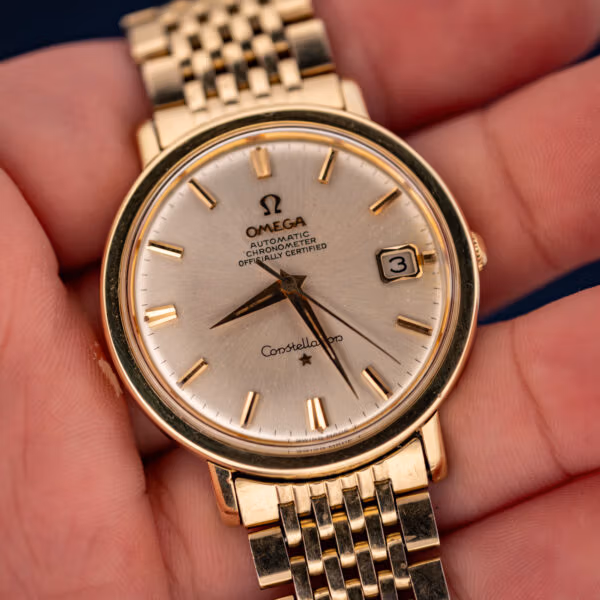 Vintage Omega Constellation 168.004 held in hand, silver chronometer dial with date window and gold bracelet