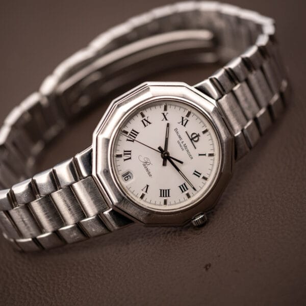 Baume & Mercier Riviera 5131.2 on its side with steel bracelet coiled, showing the twelve-sided bezel profile