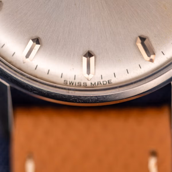 Omega caliber 285 dial lower half with SWISS MADE printed above six and faceted pink-gold baton markers