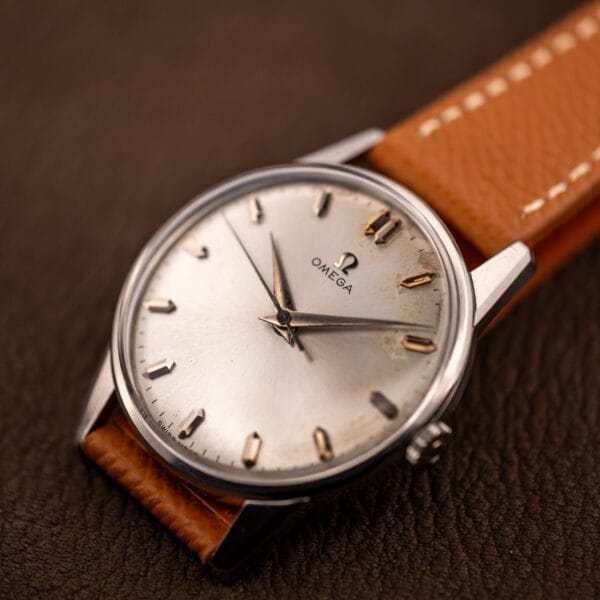 Omega 14772 SC silver sunburst dial on brown leather showing honest age toning beside the markers
