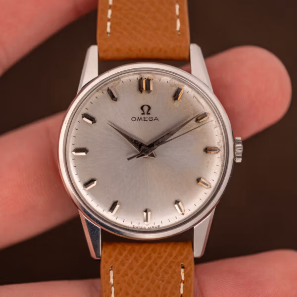 Omega caliber 285 dress watch in hand, silver sunburst dial with the Omega symbol and faceted dauphine hands