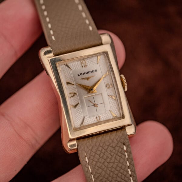 Longines 2148-1 gold-filled tank held in hand showing the full two-tone textured silver dial
