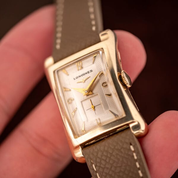 Longines 2148-1 in hand at an angle highlighting the sculpted hourglass lugs and clous-de-Paris dial