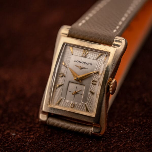 Longines 2148-1 elevated beauty shot on mud grey leather with winged hourglass dial and gold dauphine hands