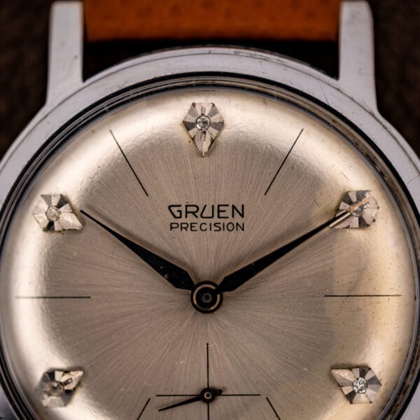 Gruen Precision silver sunburst dial macro showing GRUEN PRECISION signature, dauphine hands and diamond-set markers