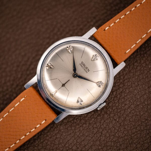 Vintage Gruen Precision diamond dial watch angled on brown leather, silver sunburst and steel case