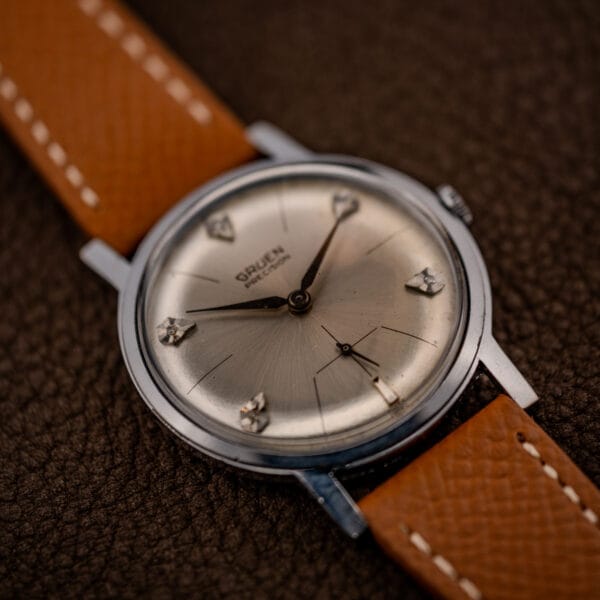 Vintage Gruen Precision diamond sunburst dial at an angle with dauphine hands and small seconds
