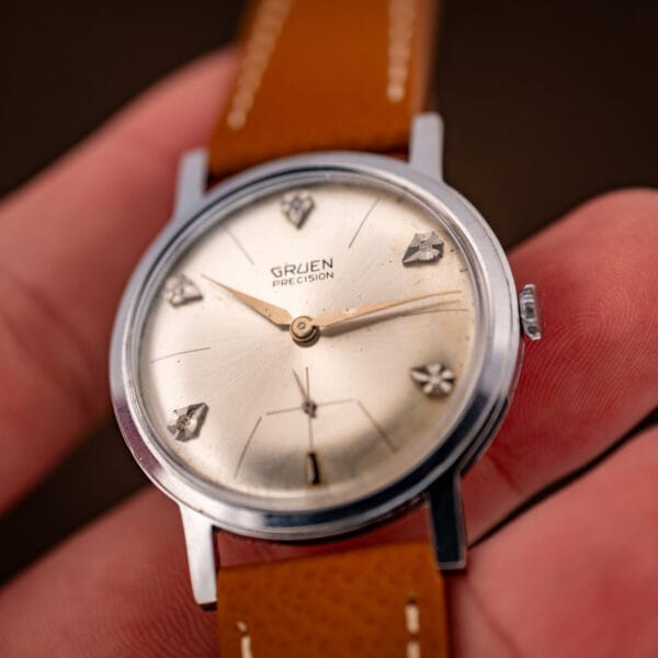 Gruen Precision diamond dial watch tilted in hand showing sunburst finish and dauphine hands