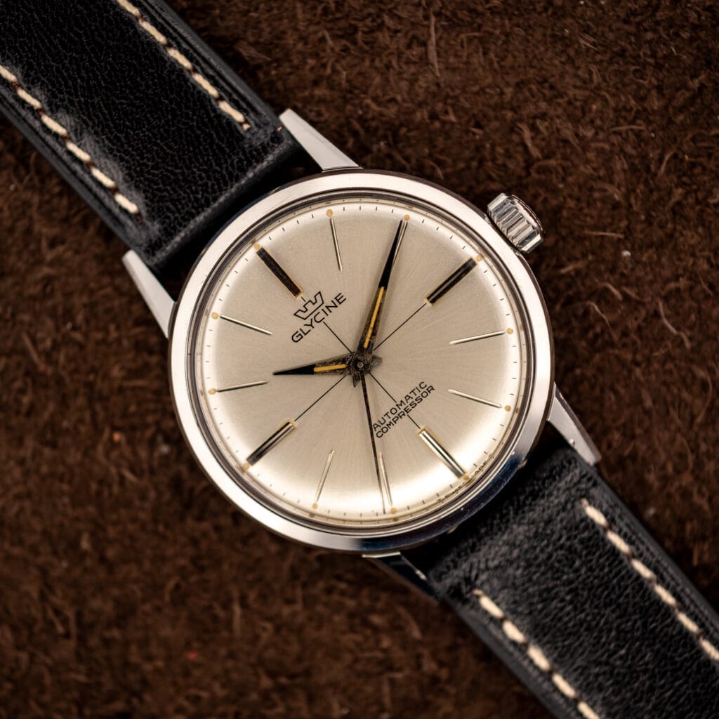 Glycine Compressor ref. 645 silver sunburst dial with applied baton markers and dauphine hands on a black leather strap
