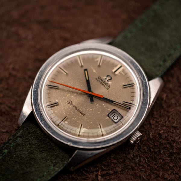 Omega Seamaster 166.028 angled view, barrel stainless steel case and orange seconds hand on green suede