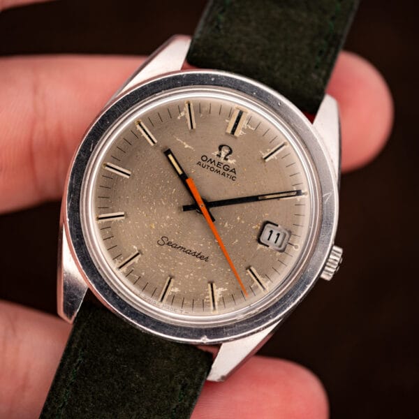 Omega Seamaster 166.028 held in hand, sandblasted silver dial and orange seconds hand in daylight