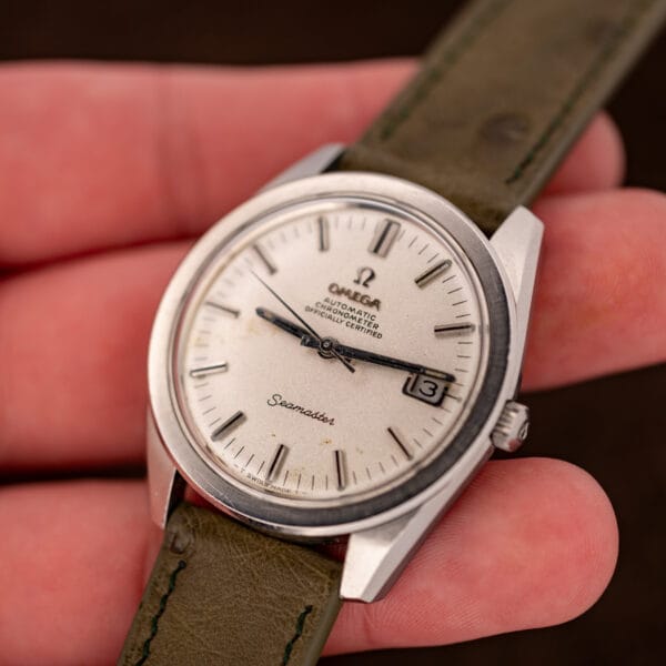 Omega Seamaster Chronometer in hand at an angle, sandblasted dial and cushion stainless steel case