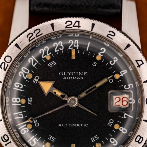 Glycine Airman black 24-hour dial close-up with red date window and aged cream luminous plots