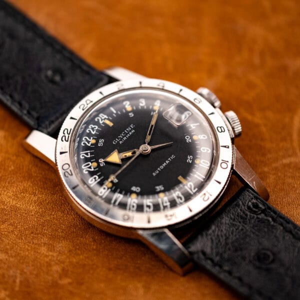 Vintage Glycine Airman automatic pilot watch angled on tan leather, black dial and rotating bezel