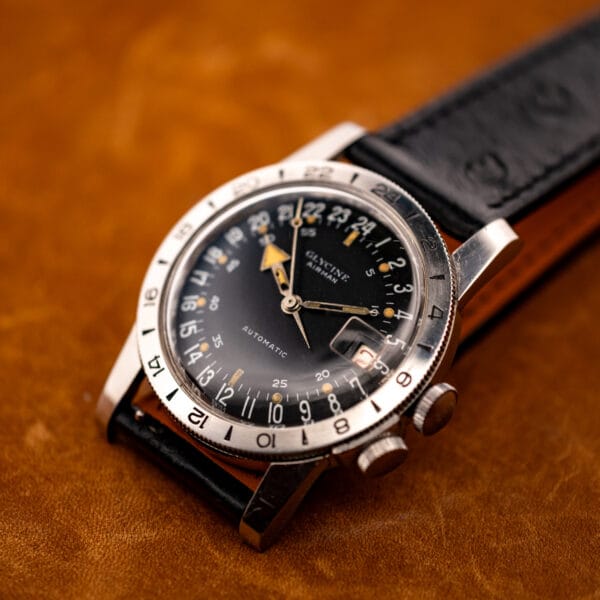 Glycine Airman steel case with faceted lugs and twin crowns on black ostrich strap, angled view
