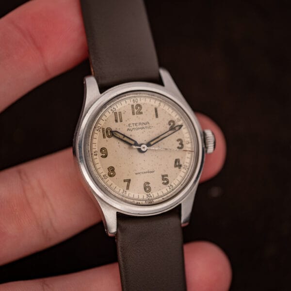 Vintage Eterna bumper automatic held in hand, full cream dial with Arabic numerals and red sweep seconds