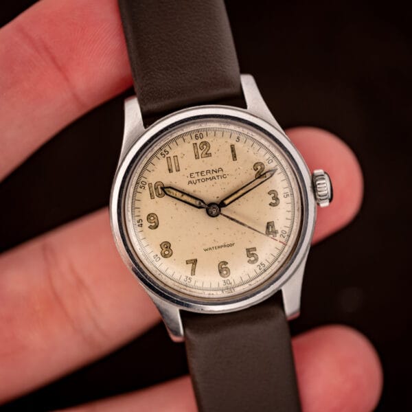 Eterna Cal. 835 in hand, dial detail showing aged toffee lume on syringe hands and red central seconds