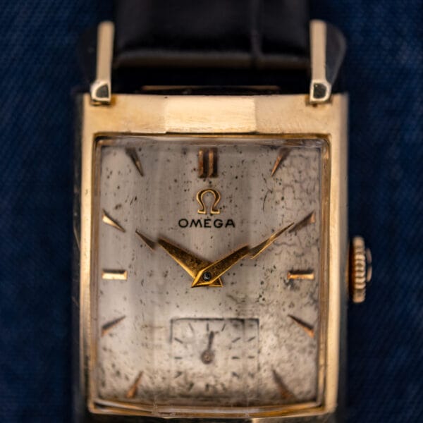 Omega Tank N-6243 dial close-up showing applied Omega logo, gold dauphine hands and foxed cream patina