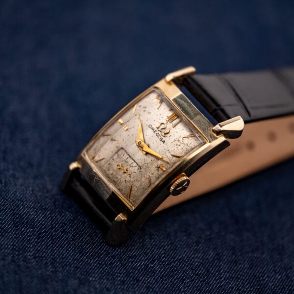 Vintage Omega Tank N-6243 angled on black leather strap showing dial patina and gold filled case