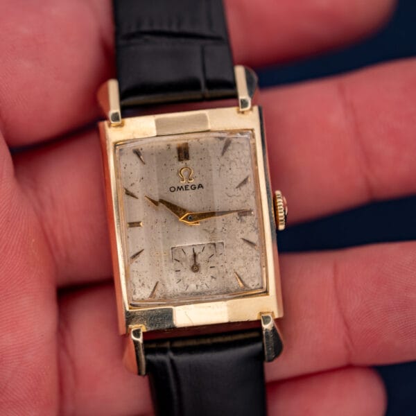 Omega Tank N-6243 held in hand showing stepped faceted fancy lugs and patinated cream dial