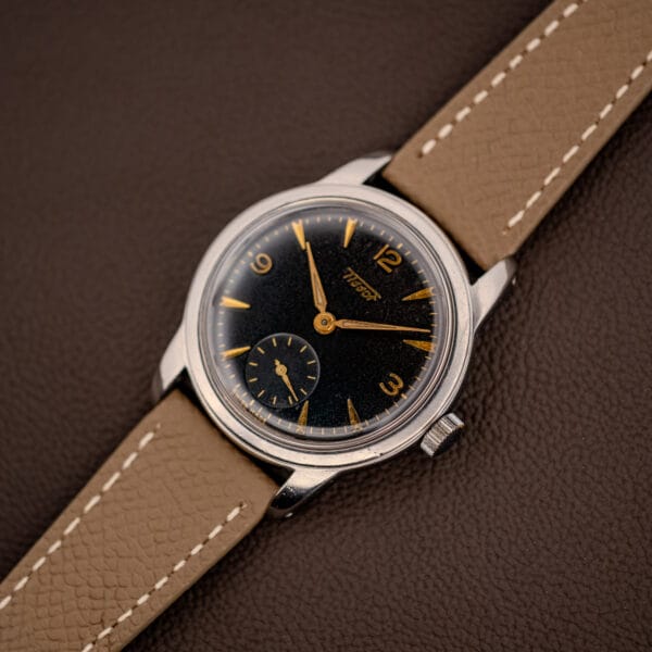 Vintage Tissot 6769 stainless steel case angled view, black gilt dial and signed crown on grey strap