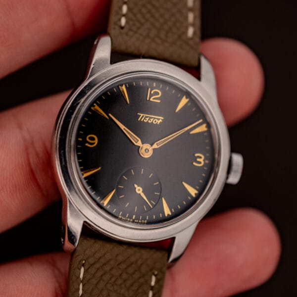 Vintage Tissot 6769 held in hand showing black gilt dial, gold numerals and SWISS MADE text