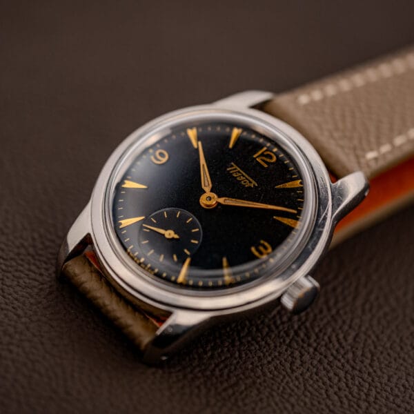 Vintage Tissot 6769 stainless steel case angled on grey leather strap, gilt dial and signed crown