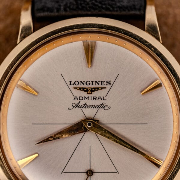 Longines Admiral dial detail showing the winged hourglass emblem, ADMIRAL Automatic script, and aged gilt dauphine hands