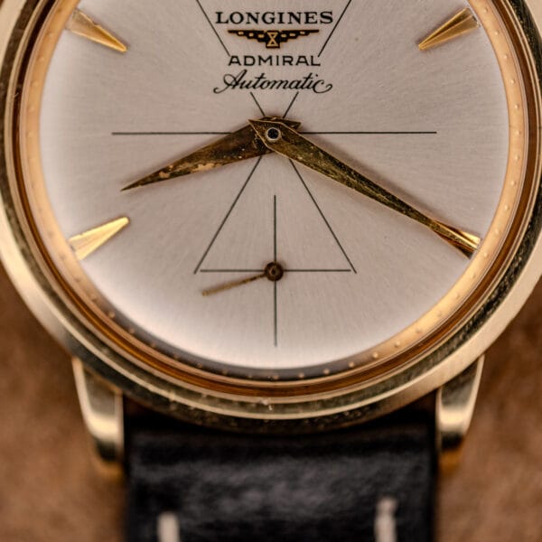 Longines Admiral silver dial close-up with faceted applied gold dart markers and dauphine hands over sunburst finish