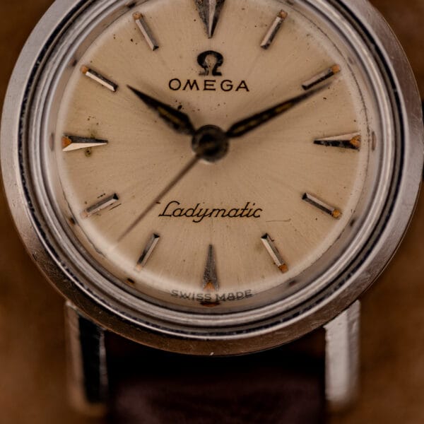 Omega Ladymatic silver sunburst dial close-up with applied Omega logo, baton markers and Ladymatic script