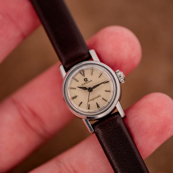 Vintage Omega Ladymatic held in fingers illustrating its compact ladies case proportions