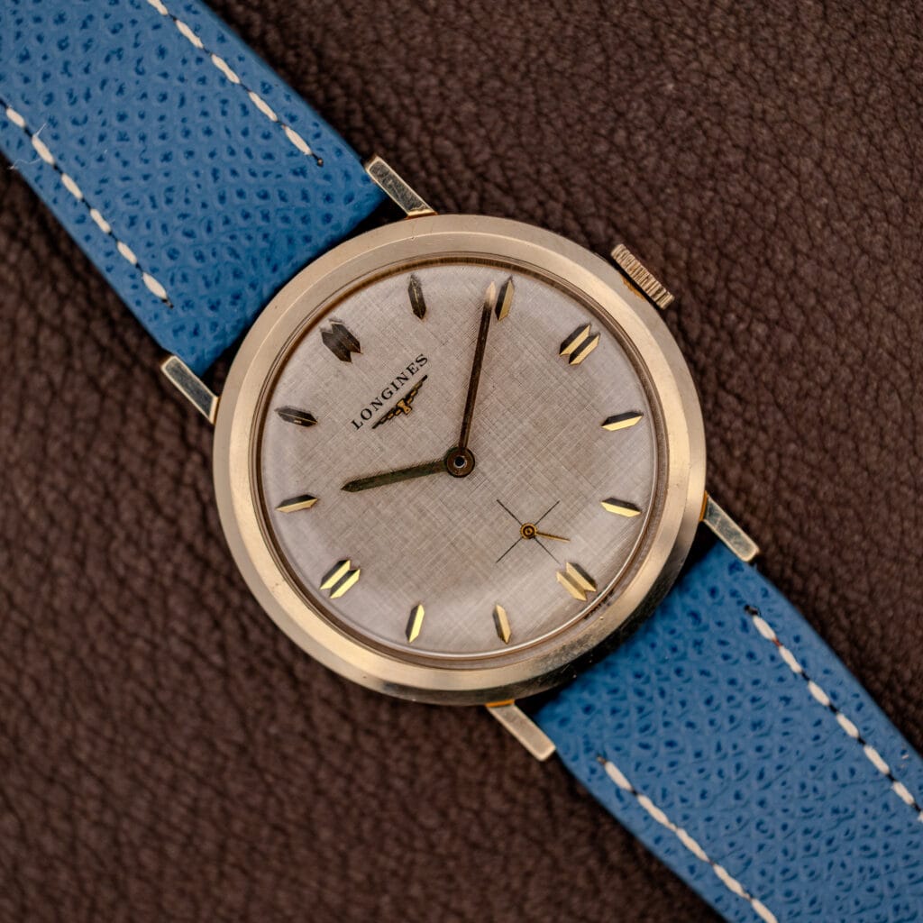 Vintage Longines Ref. 1116 white linen textured dial with gold faceted markers on a blue leather strap