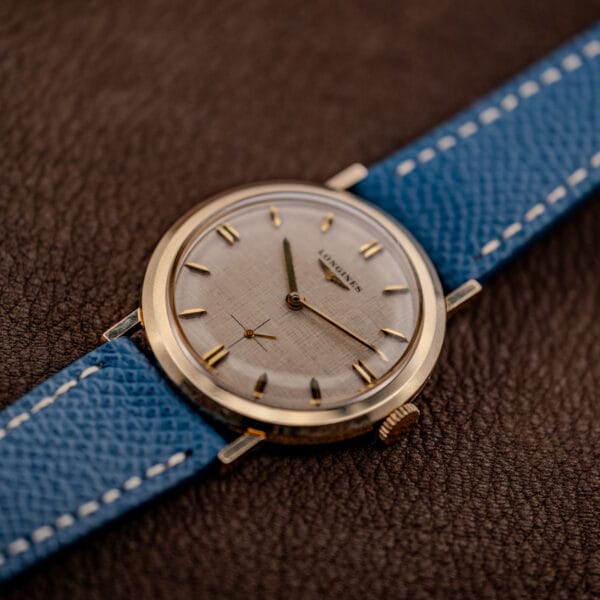 Vintage Longines Ref. 1116 angled on blue leather strap showing gold filled case wear and patina