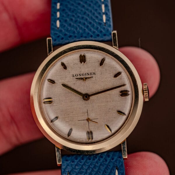 Longines 1116 frosted linen dial detail with gold dauphine hands and the winged hourglass logo