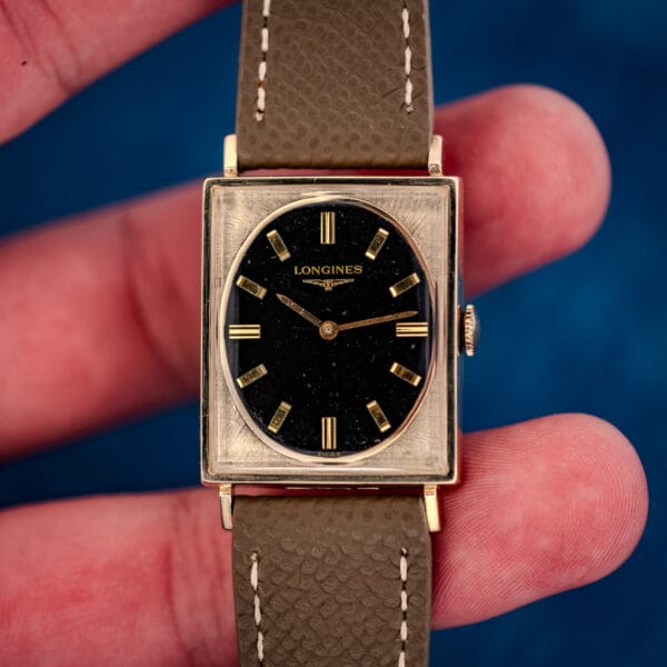 Longines 3007-528 straight-on in hand, oval black gilt dial floating inside square gold-filled case