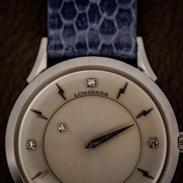 Longines mystery dial close-up of LONGINES signature, diamond markers and faceted lightning-bolt indexes on silver dial
