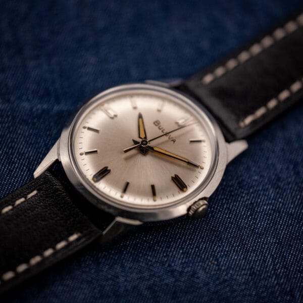 Bulova 11BLC stainless steel case angled three-quarter view on black leather strap over denim