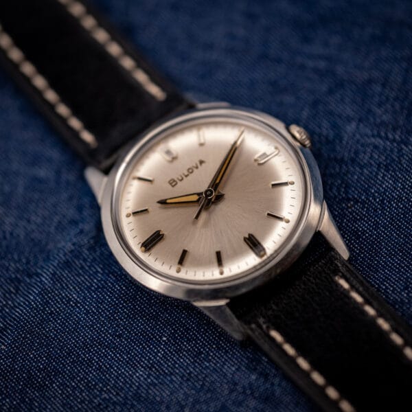 Vintage Bulova sunburst dial dress watch angled view with signed crown and black leather strap