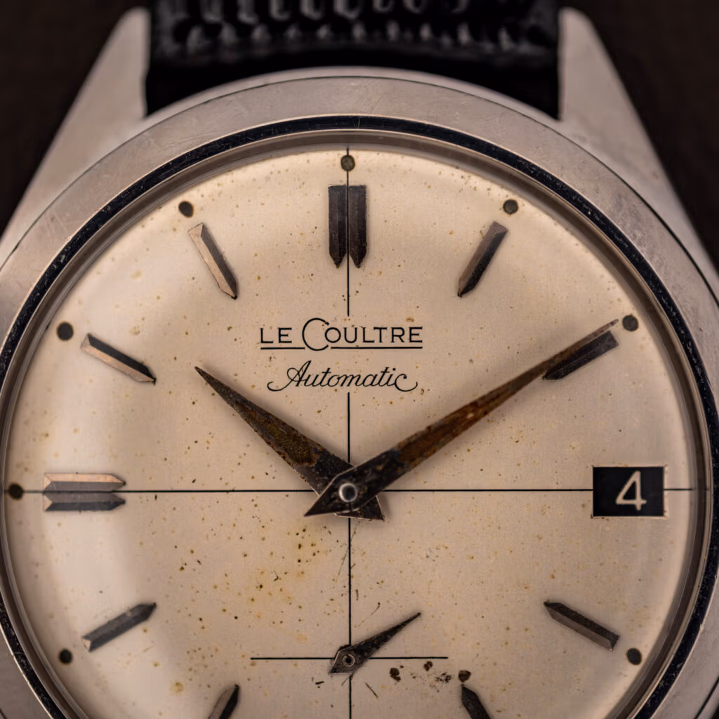 LeCoultre Automatic signature and applied faceted baton markers on aged cream E329 cross-hair dial, close up
