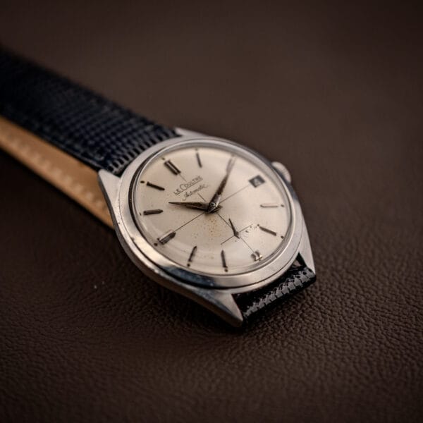 Vintage LeCoultre Automatic E329 dial and polished stainless case shown from a side angle on leather