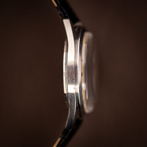 Vintage LeCoultre E329 case side showing domed crystal profile and brushed stainless flank