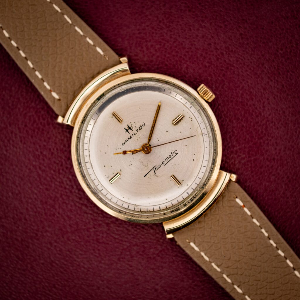Hamilton Thin-O-Matic T-406 silver sunburst dial with cross-H logo and Thin-o-matic script in gold hooded-lug case
