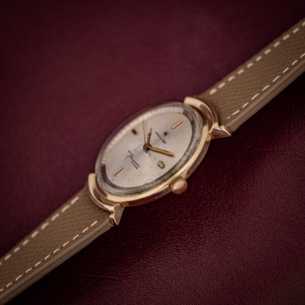 Hamilton Thin-O-Matic gold-filled hooded-lug case and silver dial photographed at an angle on burgundy leather