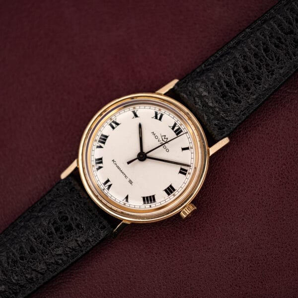 Movado Kingmatic S ref 69664 angled view, gold filled round case on black leather strap