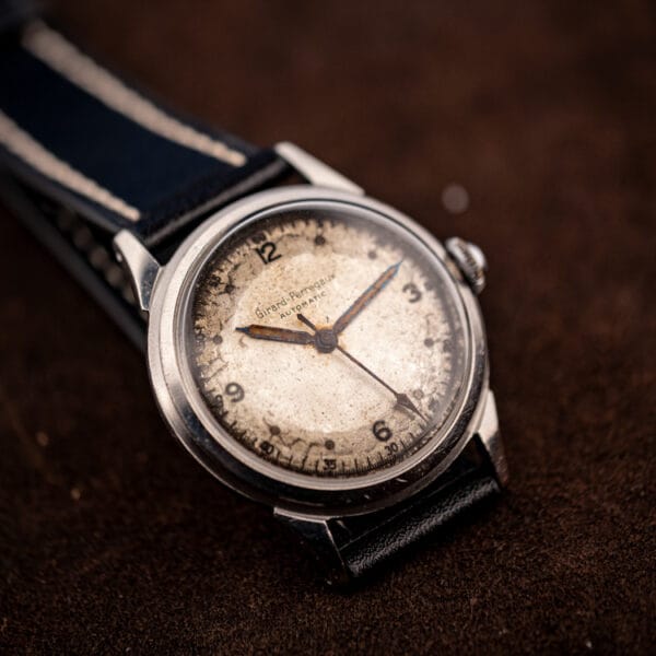 Girard-Perregaux caliber 84 automatic angled on leather strap showing the patinated off-white dial