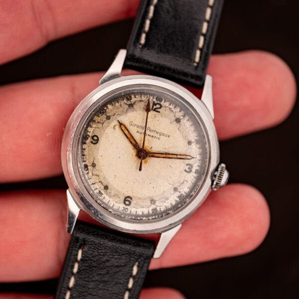 Vintage Girard-Perregaux bumper automatic held in hand showing 34mm stainless steel case and aged dial